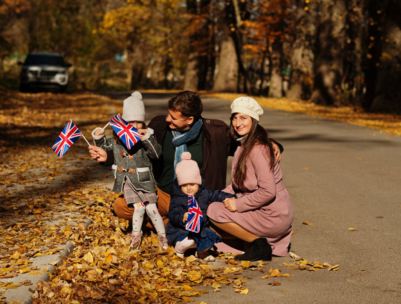Family with british flags in autumn park. Two young kids in wooly hats.